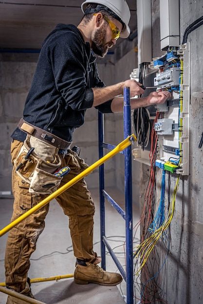 Un-electricista-trabaja-en-una-centralita-con-un-cable-de-conexion-electrica_-_-Foto-Gratis